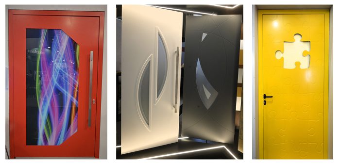 Photo of three doors; a red one with a jagged, D-shaped opening on the far left; a minimal black and white design with uniquely shaped windows in the middle; and a yellow one that looks like a puzzle with a piece missing in the top middle on the far right.