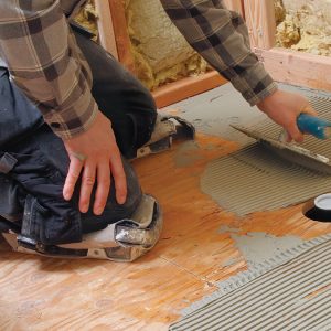 Apply a notched coat of thinset mortar to the back of the pan and the subfloor.