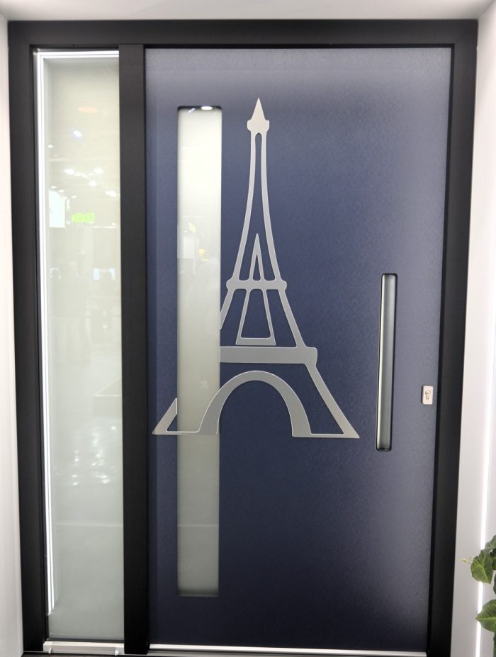 Photo of a navy door with the Eiffel Tower on it in silver.