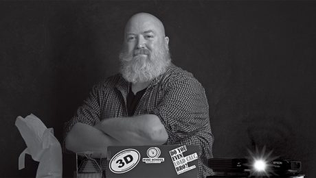 Black and white photo of Alex in front of a computer and books