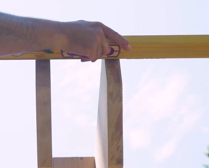 Photo of Jeremy Kassel ensuring the pergola rafters are level and evenly spaced.