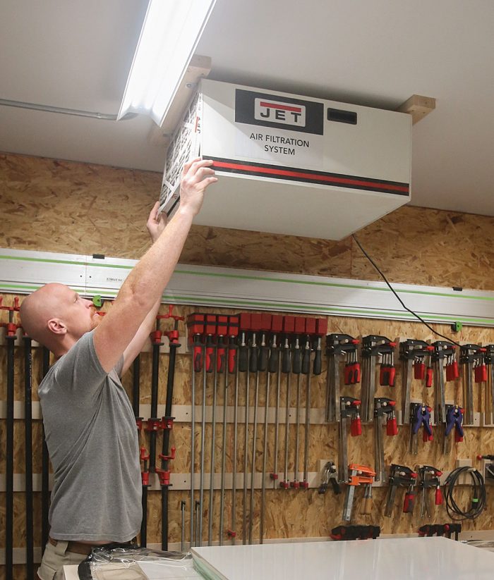 Photo of Casey Knips' installing a Jet air-filtration system in his shop.